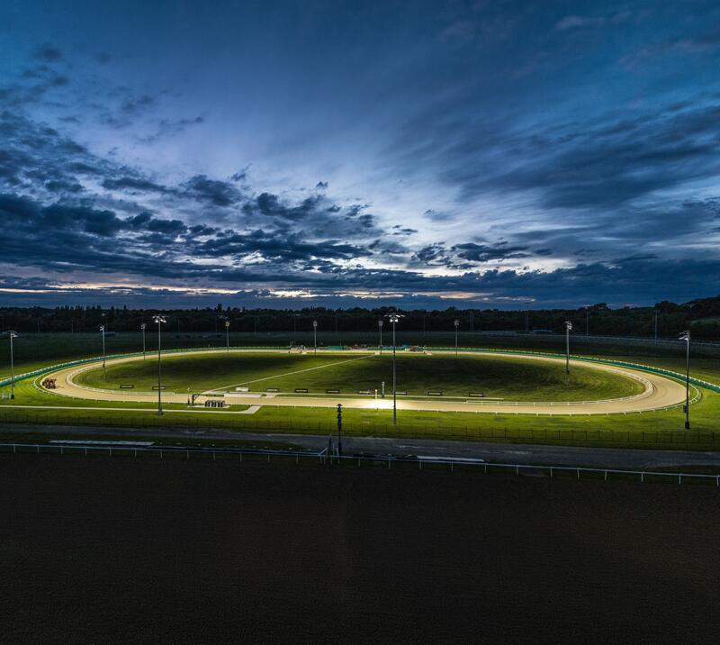 Late night view of the Dunstall Greyhounds track, lit up by spotlights.